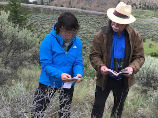 Two field naturalists use field handbooks to identify plants on a walk while learning about grasslands.